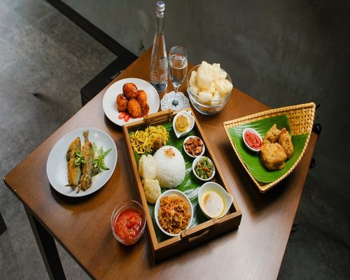 A simple wooden table set with Indonesian local food like rice, tempe, and sambal
